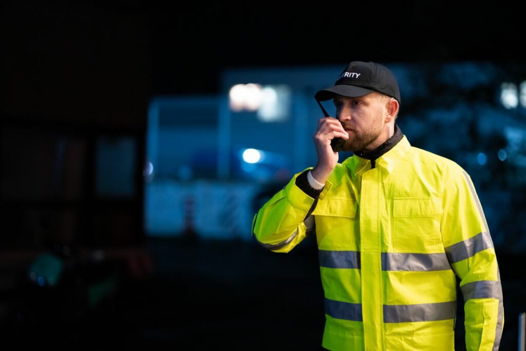 agent de sécurité parlant dans son talkie walkie en extérieur la nuit