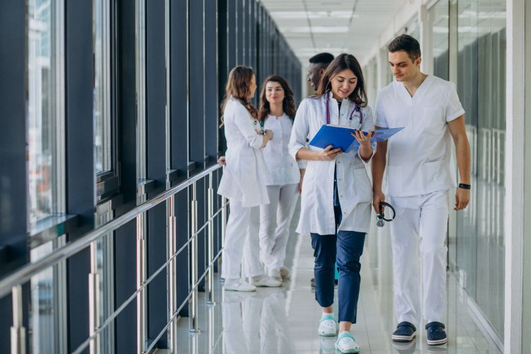 jeunes professionnels de santé en train de discuter tout en marchant dans un couloir d'hôpital