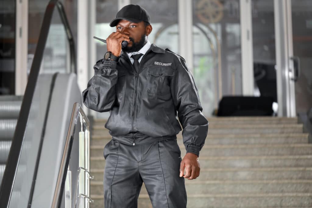 Un agent de sécurité devant un escalier en train de parler dans un talkie walkie