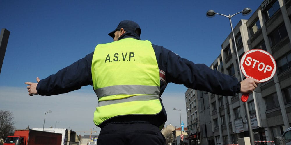 un # agent de surveillance de la voie publique avec gilet jaune qui tient un panneau stop